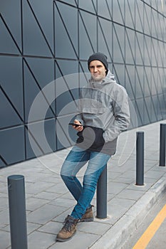 Street style portrait of handsome 30-35 years old man outdoors near the wall