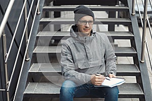 Street style portrait of handsome 30-35 years old man outdoors sitting on the stairs
