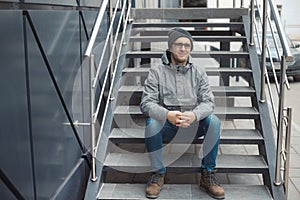 Street style portrait of handsome 30-35 years old man outdoors sitting on the stairs