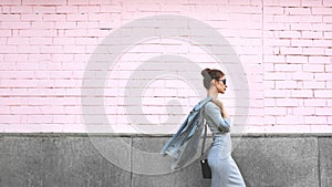 Street Style Shoot Woman on Pink Wall. Swag Girl Wearing Jeans Jacket, grey Dress, Sunglass. Fashion Lifestyle Outdoor photo