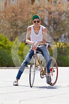 Street style on wheels. A handsome young man riding his bicycle outdoors.