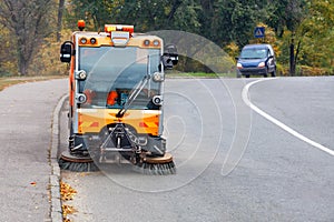 A street sweeper with two front brushes sweeps the street