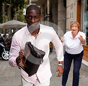 Street thief running away after stealing handbag from woman