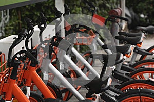 Street transportation orange hybrid rent bicycles with electronic form of payment for traveling around the city stand in