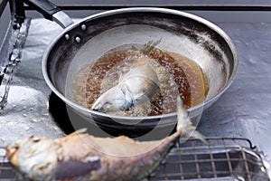 Street vender Deep fried Mackerel fish in hot pan. photo