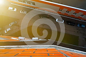 Street view from above with parked cars between buildings from apartment of multi-storey house. View from balcony down. look from