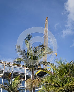 Street view of an apartment under construction. Construction crane above the building against blue sky. Auckland. Vertical format