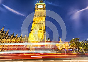 Street view of Big Ben at night with red bus trails, London - UK