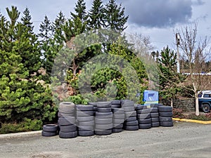 Street view of a large pile of tires outside of a car repair shop