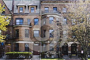 Street view of an old, red brick apartment building in Boston. Row of brownstones