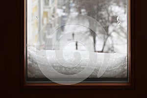 Street view from the room on a dull cloudy winter day. Snow is frozen to the glass outside