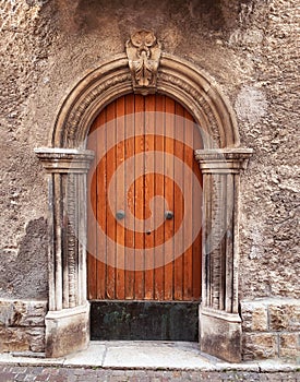 Old wooden door in the medieval city in Italy. Ancient wall of old building with wooden vintage door.