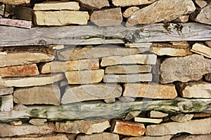 Street wall made of natural brown granite stone and dry wooden boards