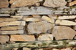 Street wall made of natural brown granite stone and dry wooden boards