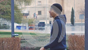 Street workout training. Male beginner doing concentration curl with resistance band on outdoor gym in the rainy park.