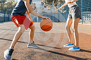 Streetball basketball game with two players, teenagers girl and boy with ball, outdoor city basketball court