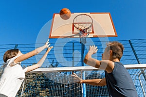 Streetball basketball game with two players, teenagers girl and boy with ball, outdoor city basketball court
