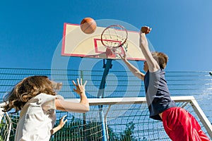 Streetball basketball game with two players, teenagers girl and boy, morning on basketball court.