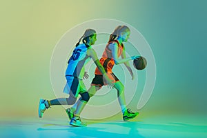 Streetball. Female basketball players, young girls, teen in action with basketball ball isolated on neoned background