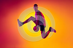 Streetballer. Male basketball player, athlete jumping with ball  on gradient yellow orange background in neon