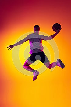 Streetballer. Male basketball player, athlete jumping with ball isolated on gradient yellow orange background in neon