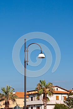 A streetlamp in front of houses and palms in italian city