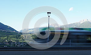 Streetlight with blurred moving regional colorful train in the foreground  in Meran city