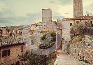 Streets and gardens of Italian medieval town with roofs of mansions at evening landscape of Tuscany.