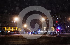Streets of Paris during snowfall at winter night