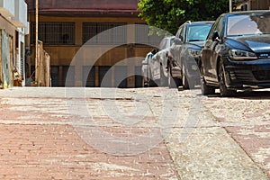 Streetscape with parked cars in a row on the right, at the far end of the fork in the broken window glass. Road is made of paved