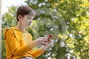 Streetstyle photo of young boy using smartphone. Communication on the go. Playing games. Gaming after school.