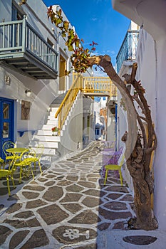 Streetview of Mykonos town with yellow chairs and tables and stairs, Greece photo