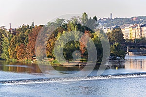 Strelecky Island with weir on Vltava river near National Theatre and the Charles Bridge, Prague, Czech Republic, sunny day