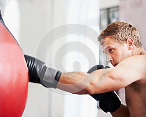 Strength and focus. A young boxer practicing with a punching ball.