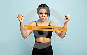 Strength and motivation. African american sportswoman doing exercises for hands, working out with resistance band