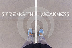Strength and weakness text on asphalt ground, feet and shoes on