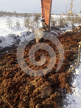 Strengthening the slope of the road with peat. Peat and excavator bucket in the background.