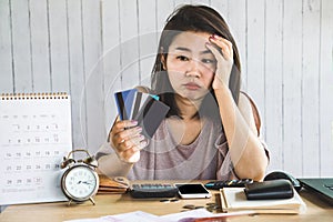 Stress Asian woman looking at credit cards in hand no money for debt