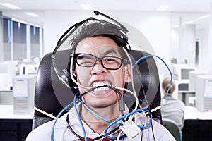 Stress businessman biting cables at office