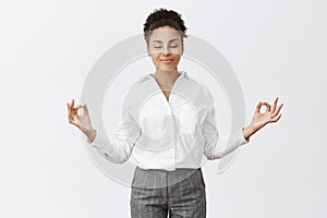 Stress free, only peace inside. Charming relaxed and carefree female in bossy outfit, raising hands in zen gesture