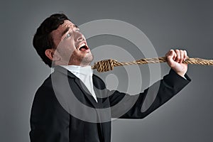 Is stress killing your career. Studio shot of a young businessman being pulled by a hangmans noose against a gray