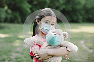 Stress little girl holding toy bear in medical protective mask