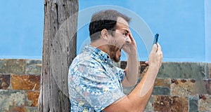 Stress and mad person, yelling and shouting to the phone in a call with blue background. Crazy Angry man calling with aggressive