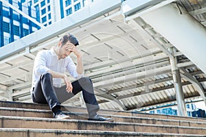 The stress man sitting alone on the stair outdoor. Young business man crying abandoned lost in depression