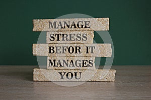 Stress management symbol. Brick blocks with words manage stress before it manages you. Beautiful green background. Wooden table.