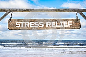 Stress relief wooden sign against blue sky and sea with waves