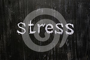 Stress word handwritten on black wood background.