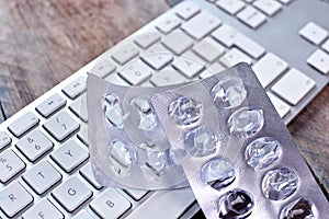 Stress at work or in business concept. The empty pack from under pills lies on the keyboard