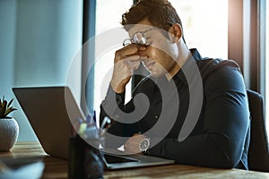 When the stress of work triggers severe migraines. Shot of a young businessman looking stressed out while working on a