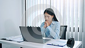 Stress young asian woman is thinking about her work and is looking at the laptop computer at the office